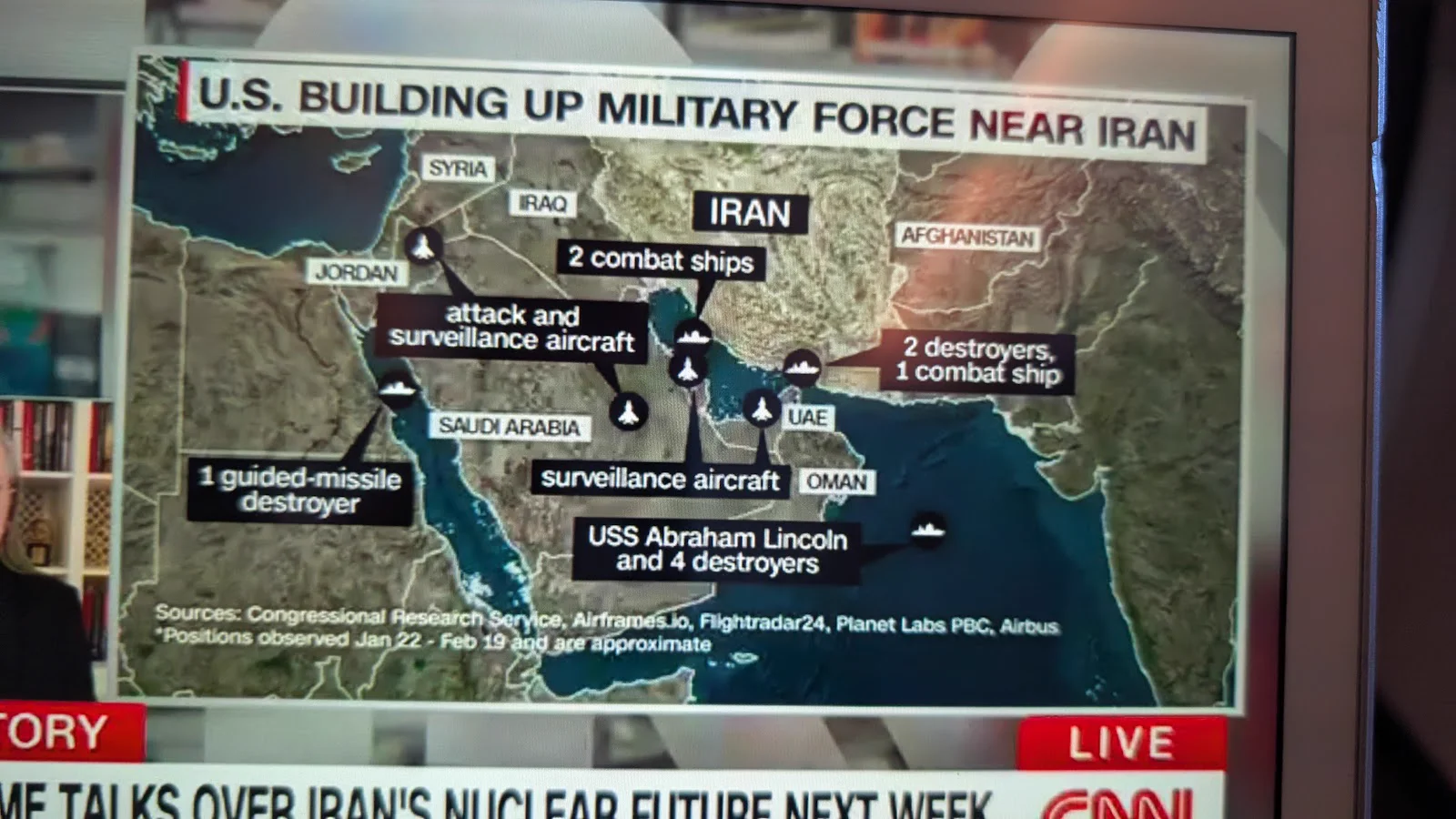 Live CNN on seatback screen: US Building Up Military Force Near Iran showing carrier strike groups, destroyers, and surveillance aircraft right under our flight path
